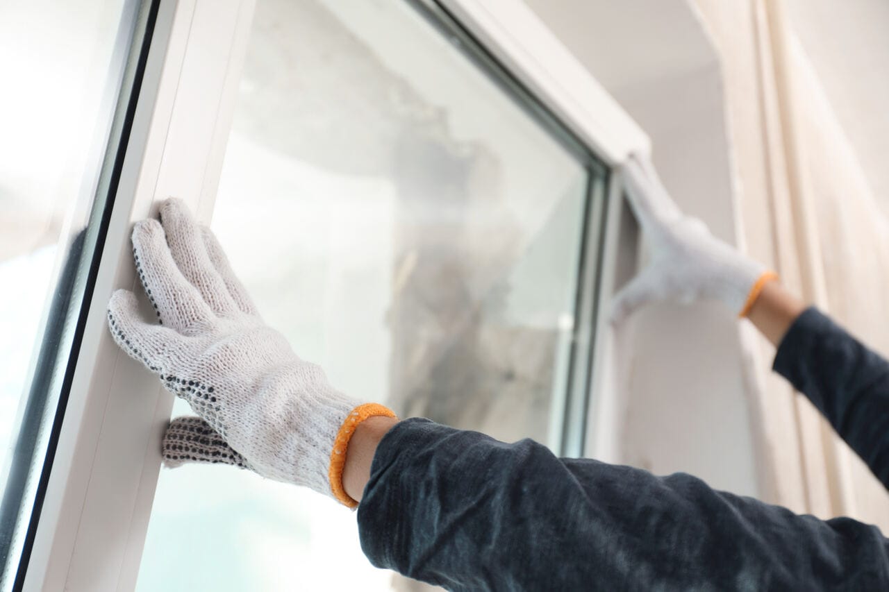 A professional is installing a window into a window frame.
