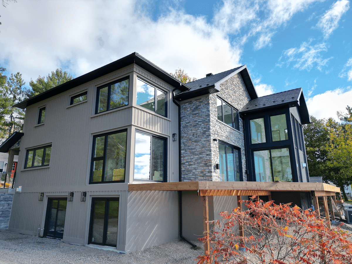 Beautiful exterior of a home with casement windows, picture windows, and multiple sliding patio door systems that are overlooking the lake.