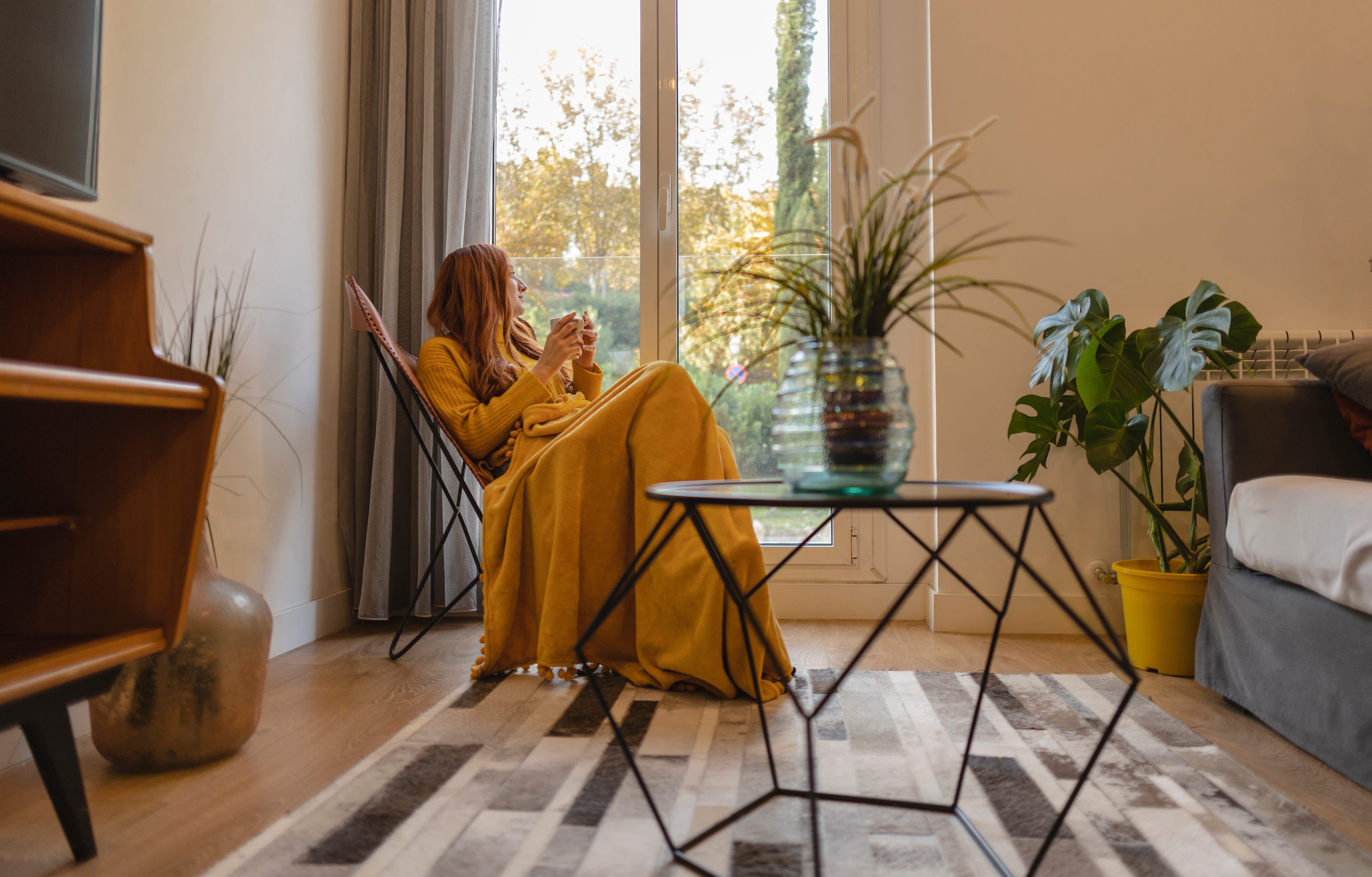 Young woman sitting and enjoying tea by her energy-efficient window and patio door.