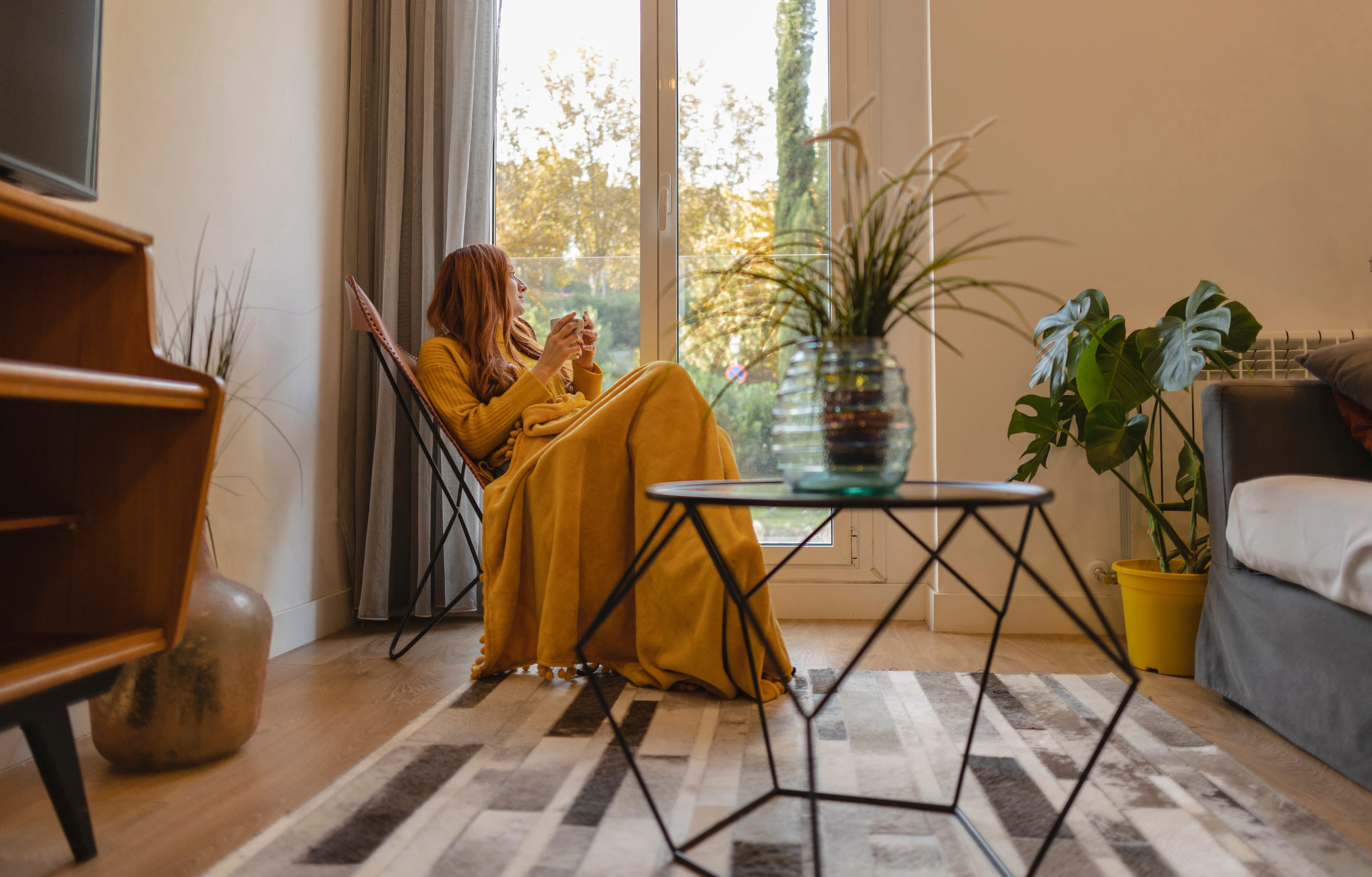 Young woman sitting and enjoying tea by her energy-efficient window and patio door.